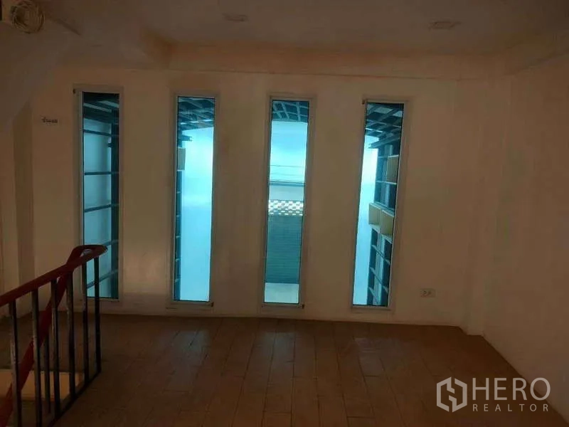 Shophouse for sale in Phra Khanong, Bangkok - Upper landing with tall, narrow windows bringing in daylight.