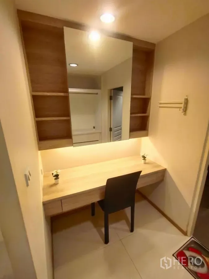 Condominium for rent in Khlong Toei, Bangkok - Bright dressing corner with a large mirror, open shelves, and a wooden vanity desk.
