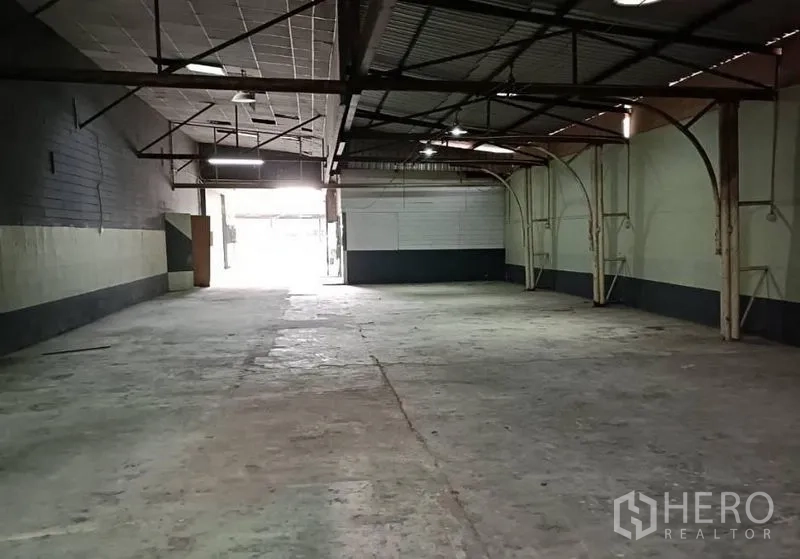 Warehouse for rent in Bang Khen, Bangkok - Rear loading bay leading to bright exit, showing roof structure and wide floor space