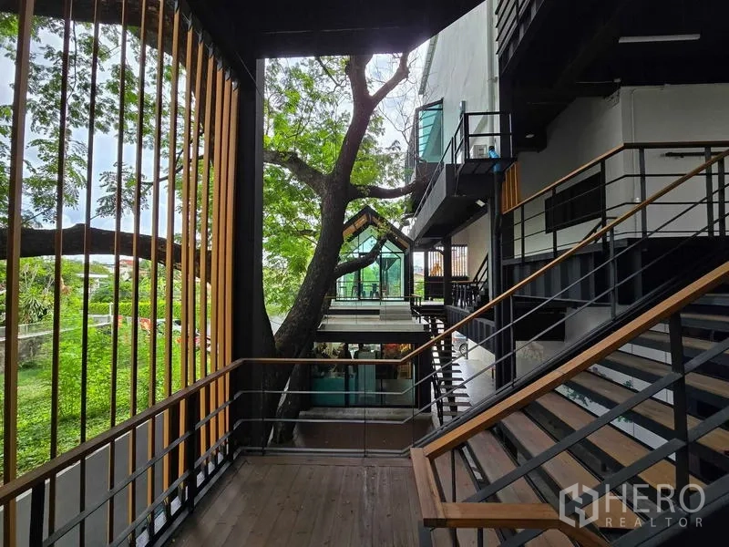 Home Office for rent in Chatuchak, Bangkok - Outdoor walkway with wooden louver screen overlooking lush greenery between buildings.
