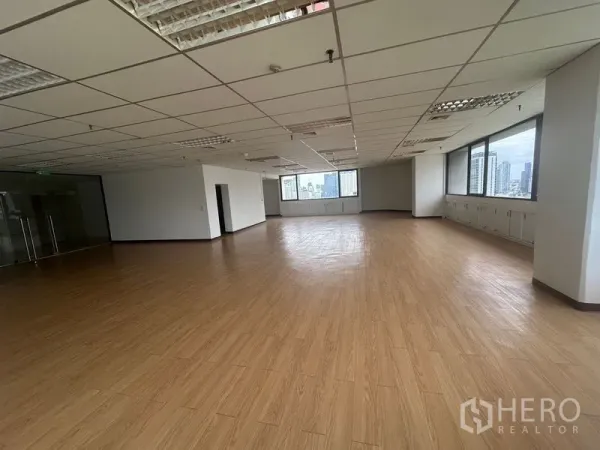 办公空间 出租在Bang Rak, Bangkok - 空置办公楼层，转角大窗与日光充足，荧光灯照明，玻璃门入口。