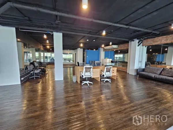 Office Space for rent in Watthana, Bangkok - Open office area with desks and swivel chairs, mirror wall, brick accent and air-conditioning units.