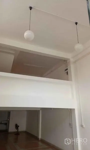 Shophouse for rent in Bangkok - High-ceiling shop interior with mezzanine and globe pendant lights.