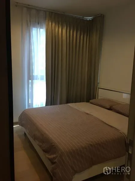 Condominium for rent in Watthana, Bangkok - Cozy bedroom with double bed, floor-to-ceiling curtains and soft natural light.