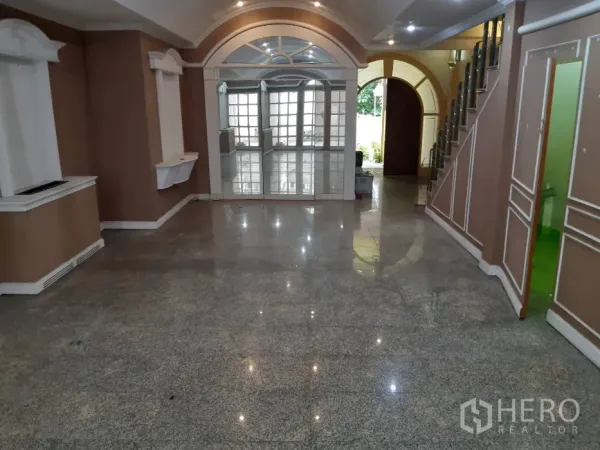 Townhouse for rent in Khlong Toei, Bangkok - Spacious living room with granite floors, arched windows and built‑in display niches.