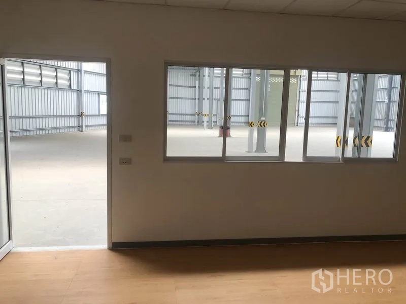货栈 出租在Bang Yai, Nonthaburi - 从办公室窗户望向仓库内部的视角，外部地面开阔。