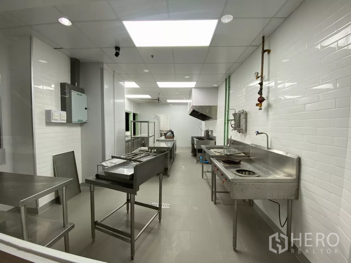 Retail Space for rent - Stainless-steel prep area with deep sinks, cooker and extractor hood in the commercial kitchen.