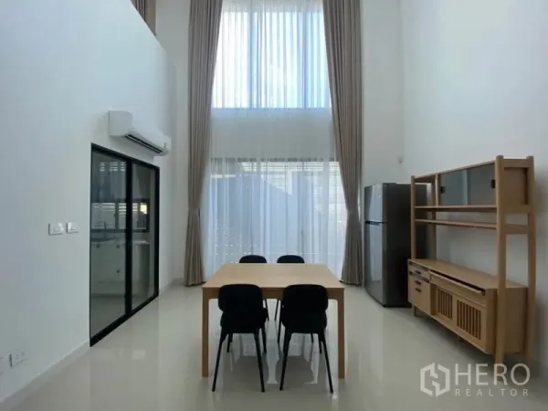 联排别墅 出租在Saphan Sung, Bangkok - 挑高客餐厅，落地窗与高帘，木质餐桌与收纳柜，采光充足。