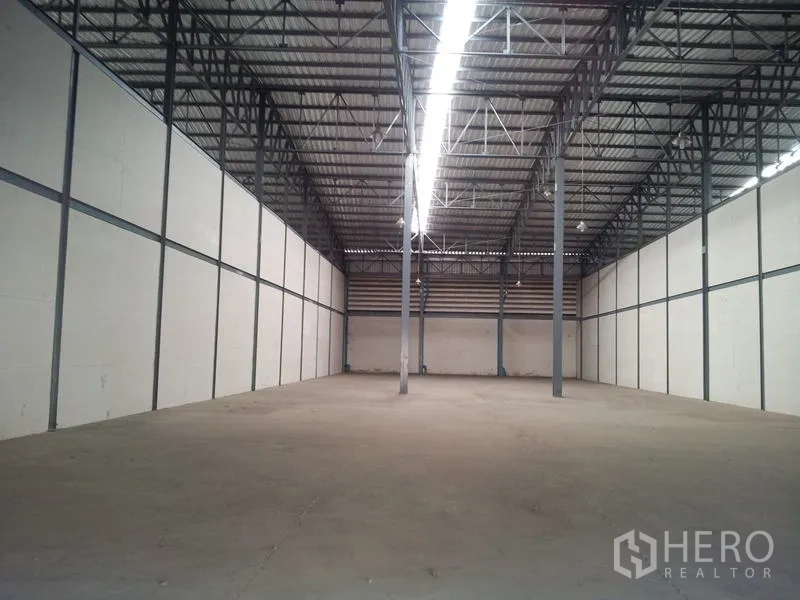 Warehouse for rent in Mueang Samut Sakhon, Samut Sakhon - Clean storage hall with high ceiling, central strip lighting and steel columns suitable for racking.