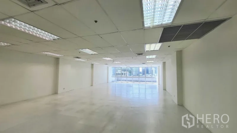 Office Space for rent in Khlong Toei, Bangkok - Spacious white office floor with grid ceiling lights and strong natural light from large windows.