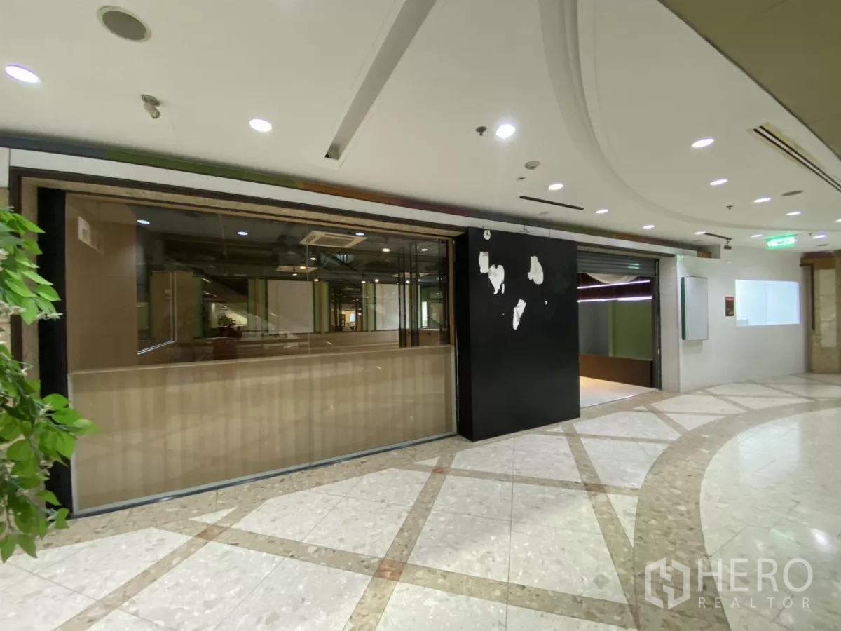 Retail Space for rent - Mall retail frontage with wide glass shopfront, black signboard and a curved marble corridor.