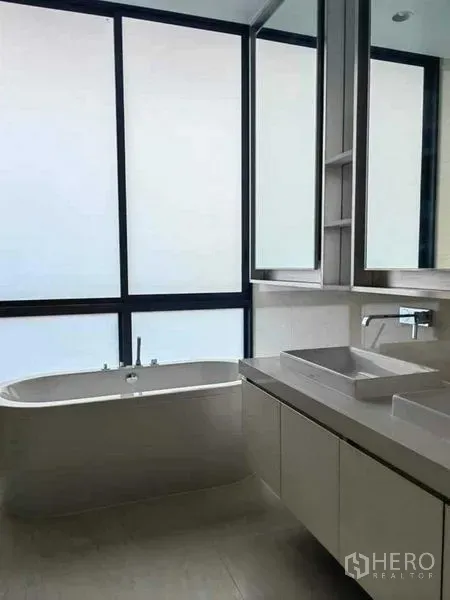 Detached House for sale in Huai Khwang, Bangkok - Contemporary bathroom with freestanding bathtub, double vanity and a large frosted window.