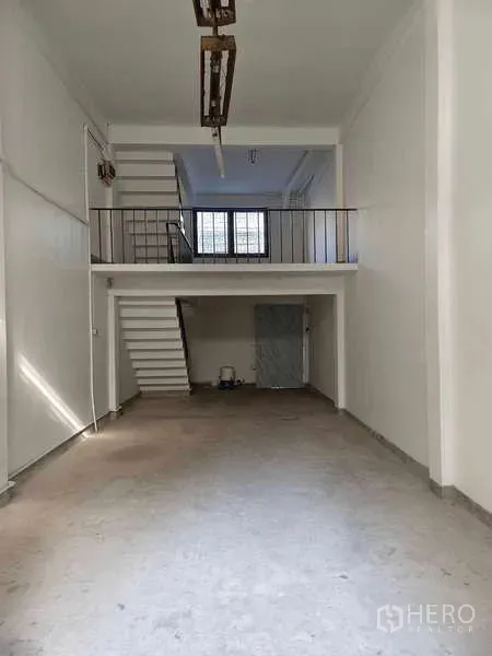 Shophouse for rent in Bang Na, Bangkok - Empty shophouse interior with high ceiling, mezzanine and rear staircase.