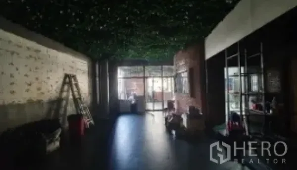 Retail Space for rent in Khlong Toei, Bangkok - Open-plan shop space with brick accent wall, ladder, and glass entrance.
