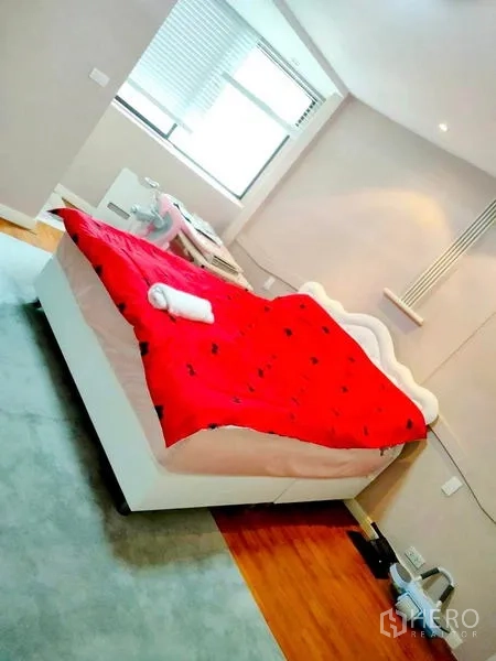 Condominium for rent in Khlong Toei, Bangkok - Cozy bedroom with corner windows and a bed dressed in a red duvet.