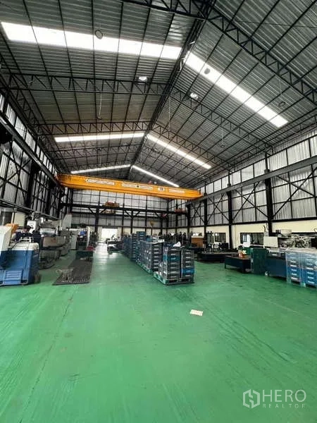 Factory for sale in Si Racha, Chon Buri - Spacious production hall featuring overhead bridge crane, skylights and machinery rows.