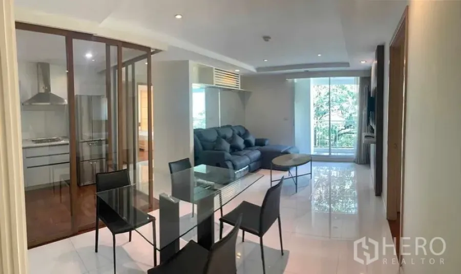Condominium for rent or sale in Khlong Toei, Bangkok - Open living-dining area connected to the enclosed kitchen and balcony with greenery.