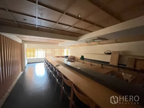 Retail Space for rent - Spacious bar seating area with timber counter and built-in shelves, natural light from wide windows.