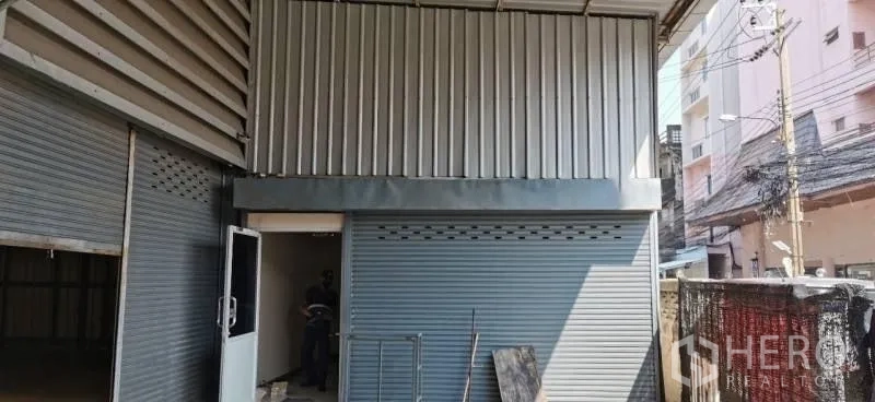 Warehouse for rent in Huai Khwang, Bangkok - Side elevation showing roller shutters, metal cladding, and service door along the lane.