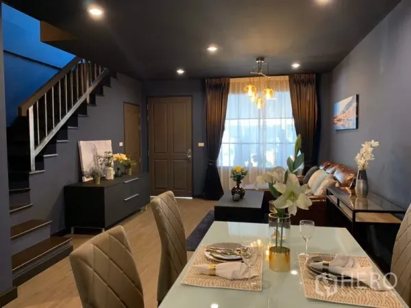 Townhouse for rent in Bang Kapi, Bangkok - Open-plan living and dining area with staircase, chandelier and large window.