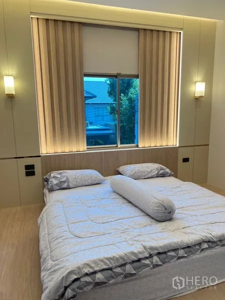 Detached House for sale in Bang Kapi, Bangkok - Guest bedroom with window blinds, wall sconces and a double bed.