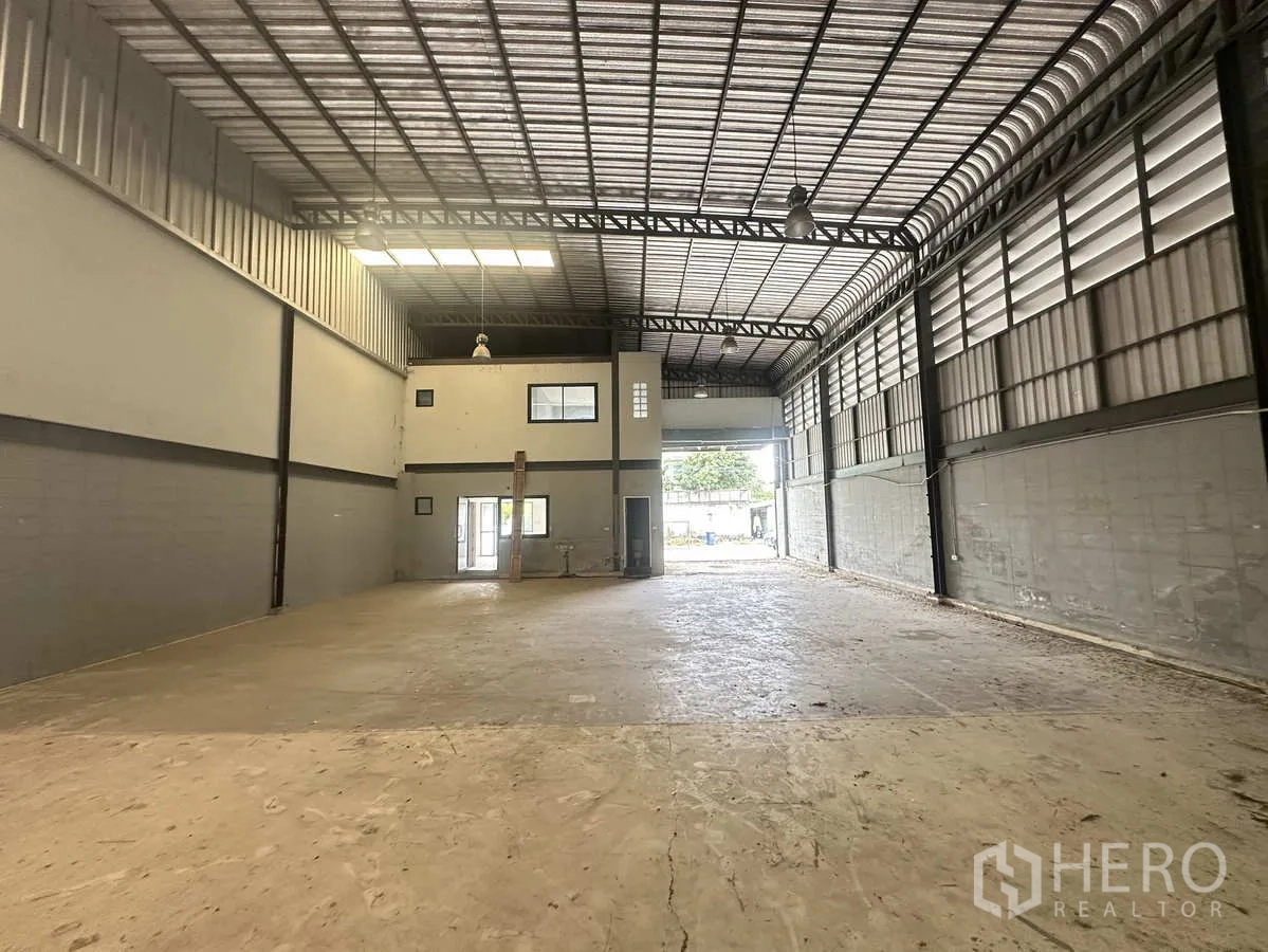 Warehouse for rent or sale in Bang Yai, Nonthaburi - Open warehouse floor looking toward the front office block and wide entrance gate.