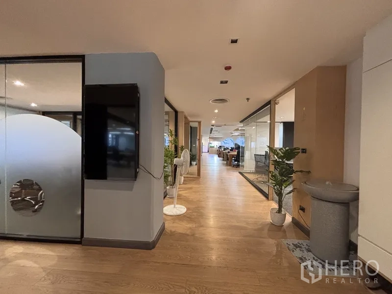 ออฟฟิศ for rent in Bang Rak, Bangkok - โถงทางเดินมีต้นไม้ตกแต่งและผนังกระจกกั้นห้องทำงาน
