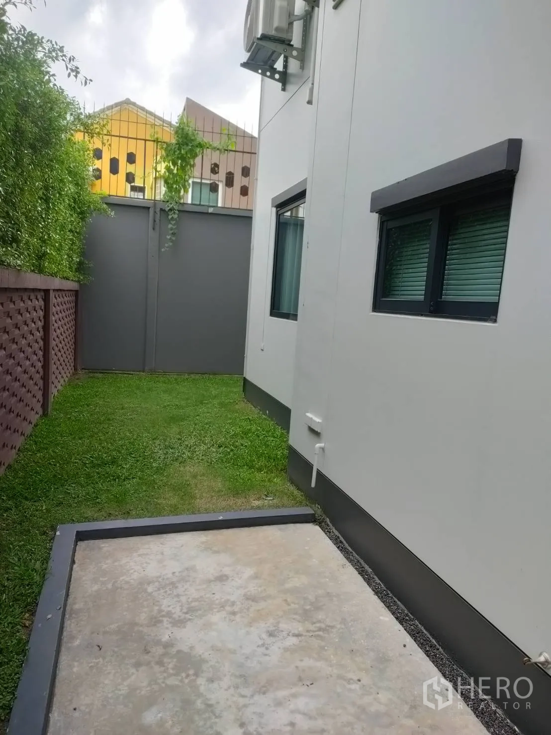 Detached House for rent or sale in Lam Luk Ka, Pathum Thani - Another side yard view with concrete pad, lawn, and privacy fence.