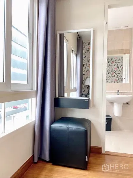 Townhouse for rent in Prawet, Bangkok - Cozy vanity corner by the window with mirror and stool next to a bathroom entrance.