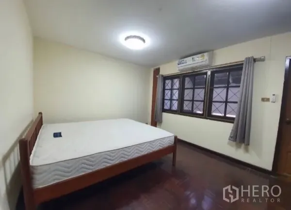 Townhouse for rent in Watthana, Bangkok - Bedroom with wooden floors, large windows and air conditioning.