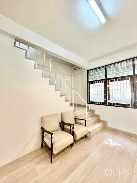 Home Office for rent in Khlong Toei, Bangkok - Stair landing with two armchairs beside a window with security grilles.