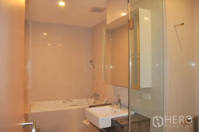Condominium for rent or sale in Watthana, Bangkok - Modern bathroom with soaking tub, glass shower screen, and vanity.