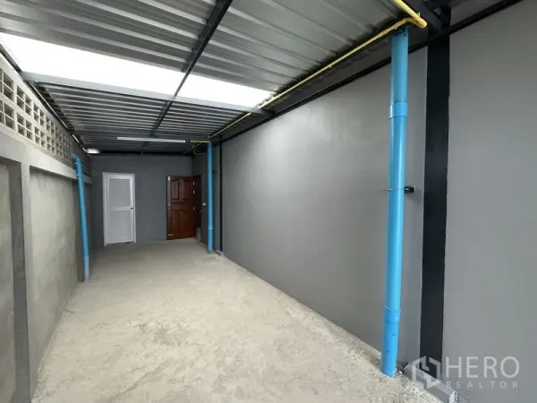 Warehouse for rent in Lam Luk Ka, Pathum Thani - Covered side corridor with utility piping and access doors to service areas.