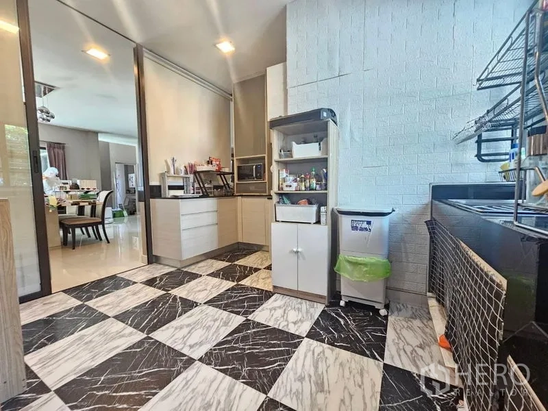 Detached House for sale in Prawet, Bangkok - Semi‑open kitchen with black and white chequered floor, built‑in cabinets and shelving.