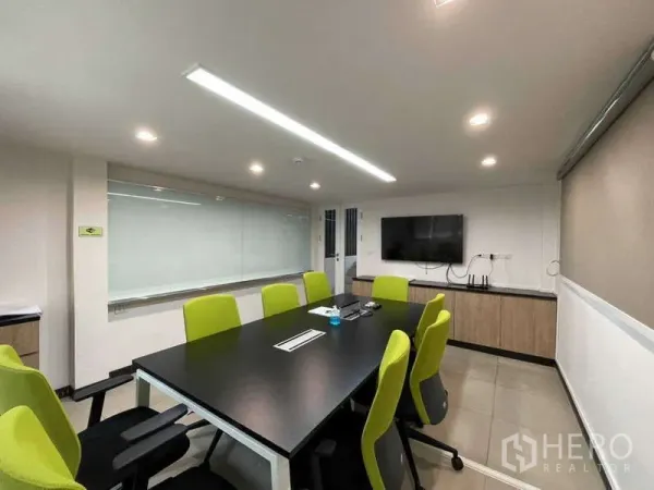Home Office for rent in Watthana, Bangkok - Conference room with whiteboard, wall-mounted TV, LED lights and green chairs.