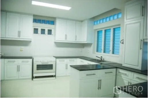 独立式住宅 出租在Khlong Toei, Bangkok - 现代厨房，白色橱柜、黑色台面、烤箱与通风窗。