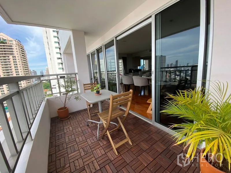 Condominium for rent in Sathon, Bangkok - Balcony with table and chairs, potted plants and skyline views.