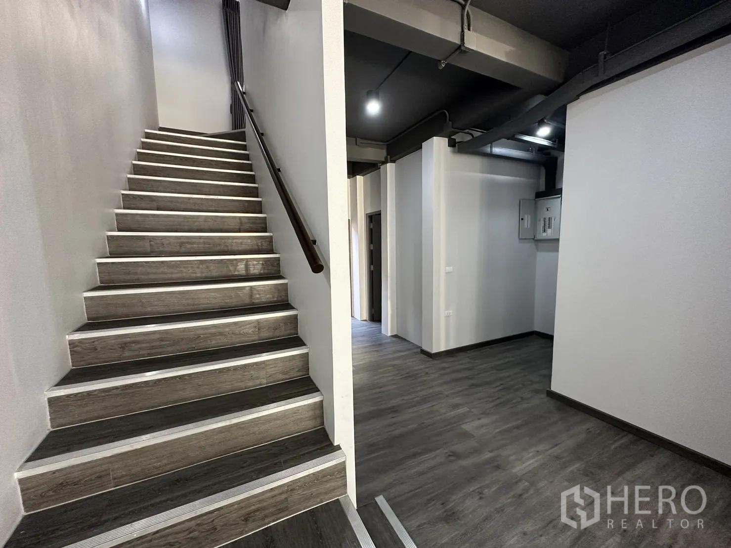 Home Office for rent or sale in Suan Luang, Bangkok - Wide stairwell and hallway with exposed ceiling details and dark wood steps.