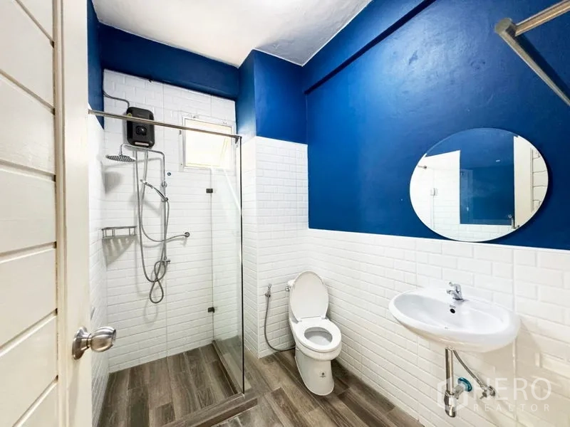 Townhouse for rent or sale in Suan Luang, Bangkok - Bathroom with blue accent wall, white subway tiles and glass-enclosed shower