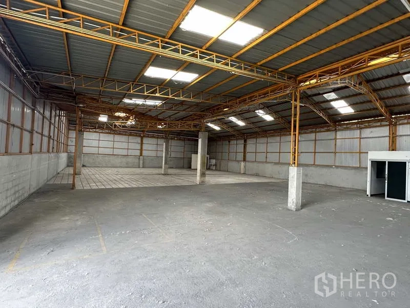 Warehouse for rent in Mueang Pathum Thani, Pathum Thani - Clear-span warehouse space featuring metal roof panels, skylights, and marked floor zones.