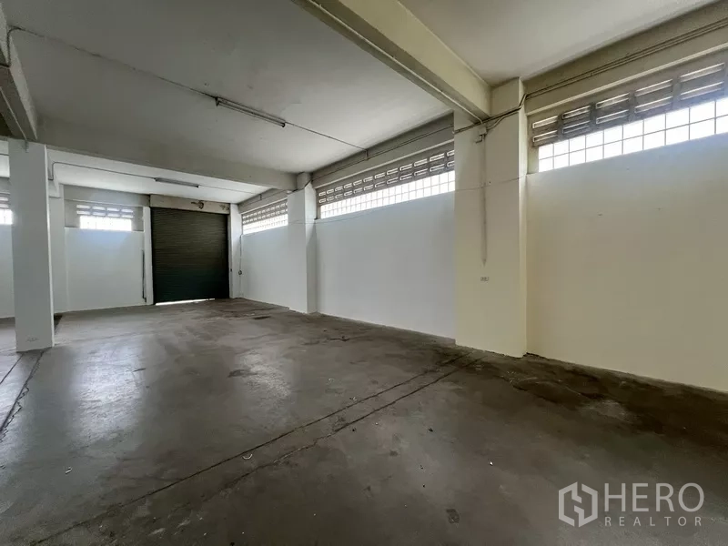 Warehouse for rent in Phra Khanong, Bangkok - Open-plan storage hall with columns, glass-block windows and smooth concrete floor