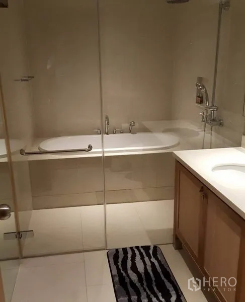 Condominium for rent or sale in Khlong Toei, Bangkok - Bathroom with glass enclosure, bathtub and vanity.