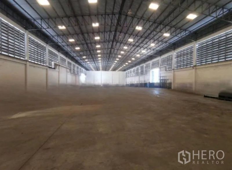 Warehouse for rent in Bang Phli, Samut Prakan - Expansive warehouse interior with high steel truss ceiling, ventilation louvers, and concrete floor.