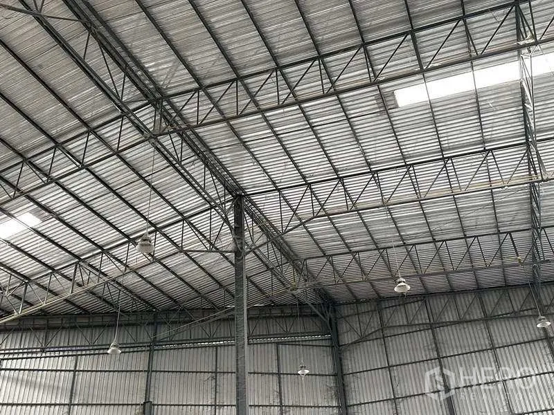 Warehouse for rent in Si Racha, Chon Buri - Close-up of steel truss roof with high-bay lighting and skylight panels.
