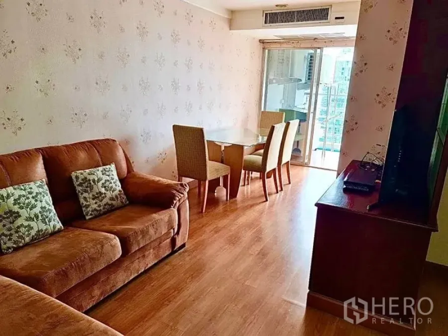 Condominium for rent in Khlong Toei, Bangkok - Living room with brown sofa, TV cabinet and access to balcony.