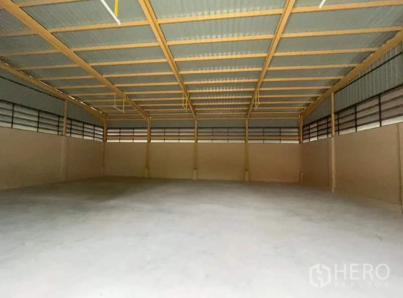 Warehouse for rent in Khlong Sam Wa, Bangkok - Spacious empty warehouse interior showing high steel truss roof, ventilation panels, and smooth concrete floor.