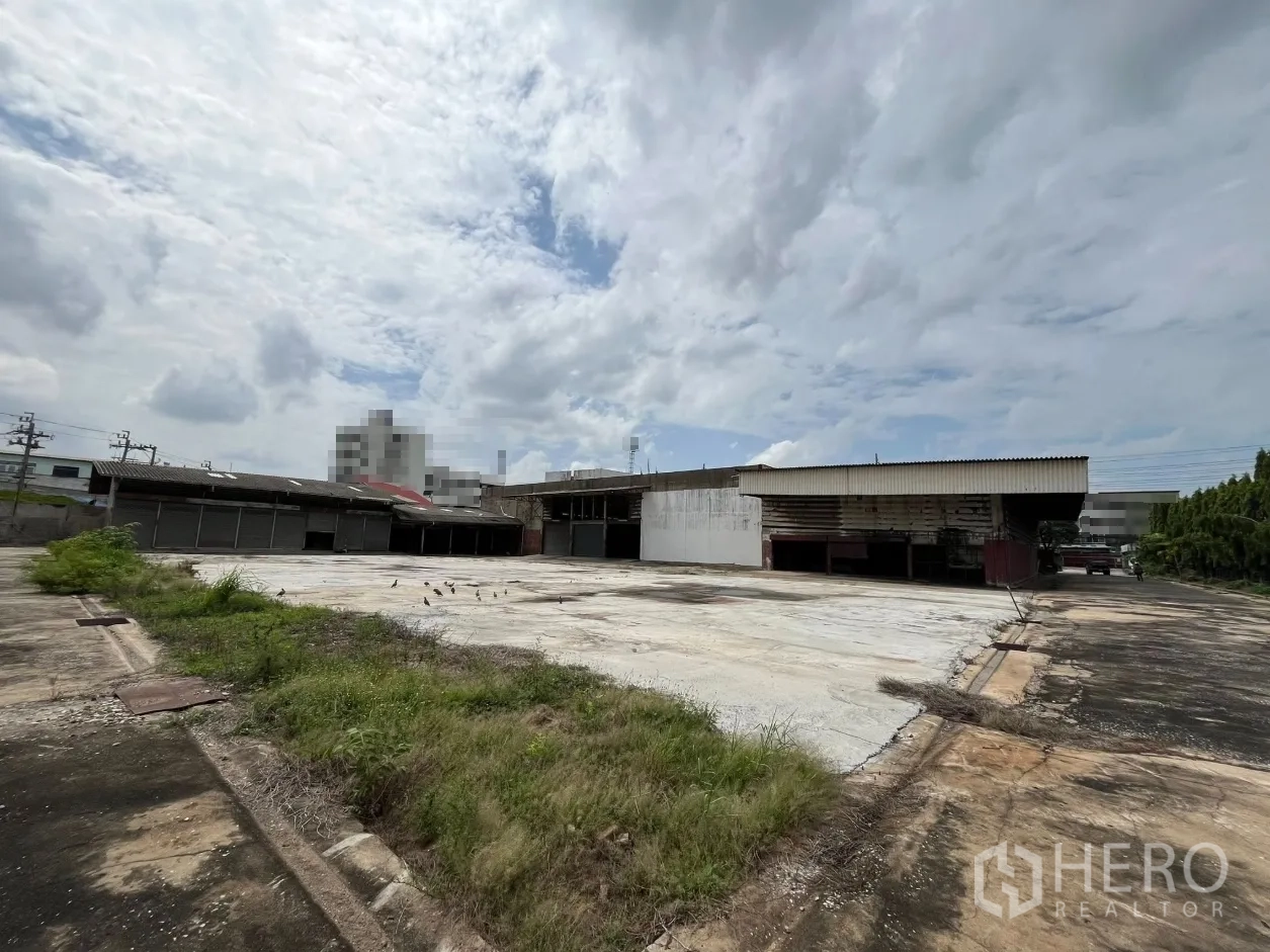 Factory for rent in Phra Pradaeng, Samut Prakan - Large open hardstand yard with multiple warehouse buildings and shutter doors.