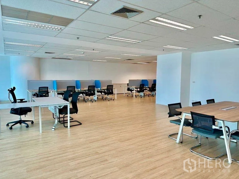 Office Space for rent - Flexible office area with mixed desks, collaboration table, light wood floors and drop-ceiling lighting.