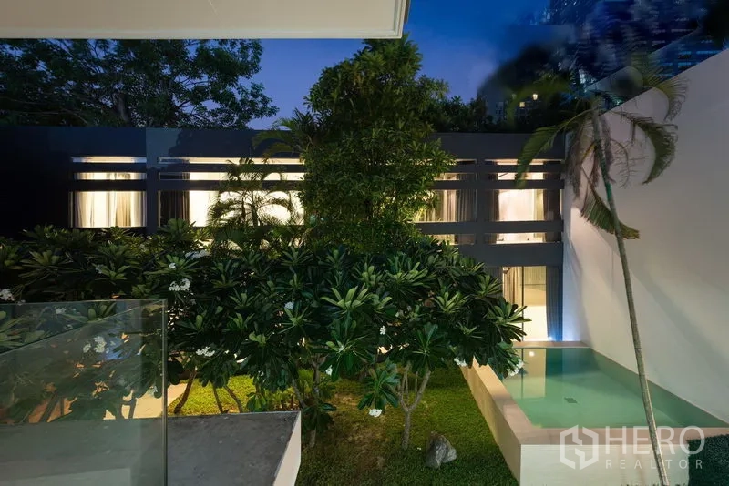 Home Office for rent in Khlong Toei, Bangkok - Evening balcony view over a lush garden and plunge pool beside a modern building.