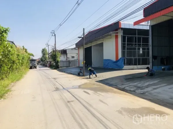 Warehouse for rent in Bang Kapi, Bangkok - Row of modern warehouses with wide roller door and driveway facing a two-lane road in Bang Kapi, Bangkok.